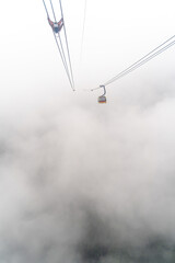 Tourists traveling in transportation machine basket on Fansipan mountain at Sapa north of Vietnam. Misty morning in mount Fansipan.