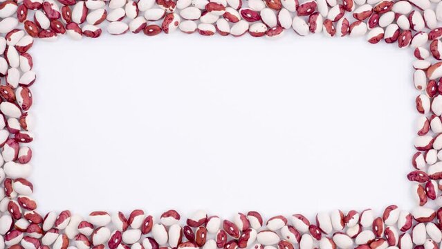 On white surface each side is filled with red-white beans until it forms frame in shape of rectangle, nutritious food, protein, healthy diet, grains containing protein. Close up, 4K Ultra HD.