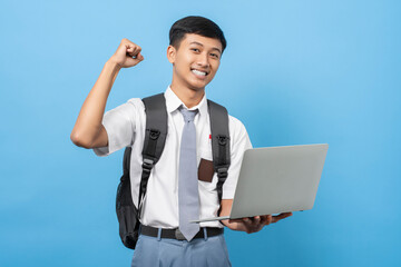 Indonesian senior high school student Holding and using laptop isolated on blue background. Pelajar...