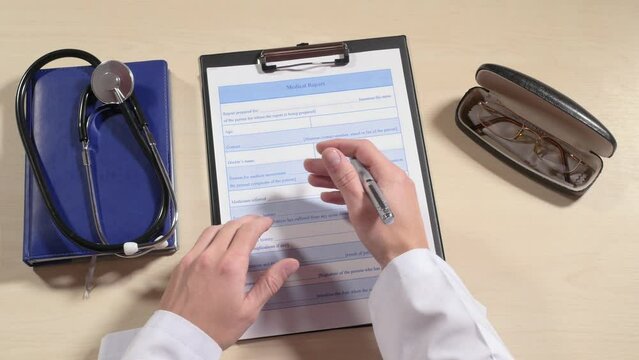 Doctor's hand takes pen, tries to fill in medical card, takes glasses from spectacle case, takes magnifying glass to read, stethoscope on table, short sighted, medicine. Close up, 4K Ultra HD.