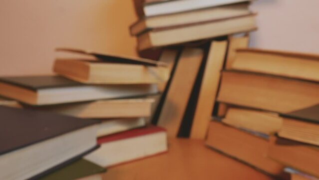 Dolly shot zoom in slow move between stacks of old volumes to a pencil between pages of a vintage book on a library table or bookshelf