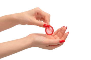 A red condom in a woman hand with red nails isolated on white background.
