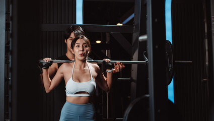 Fototapeta na wymiar Woman working out Bodybuilder with coaching assistance to support weights at the gym. bodybuilder doing exercises with barbell. training sport healthy lifestyle bodybuilding...