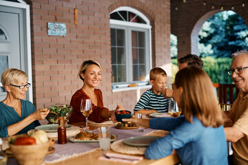 Happy multigeneration family eats lunch on patio.