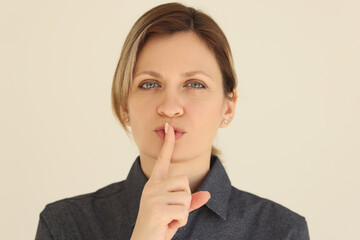 Woman puts index finger to mouth asking to keep silence