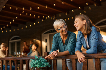 Happy senior woman talks to her teenage granddaughter on terrace.