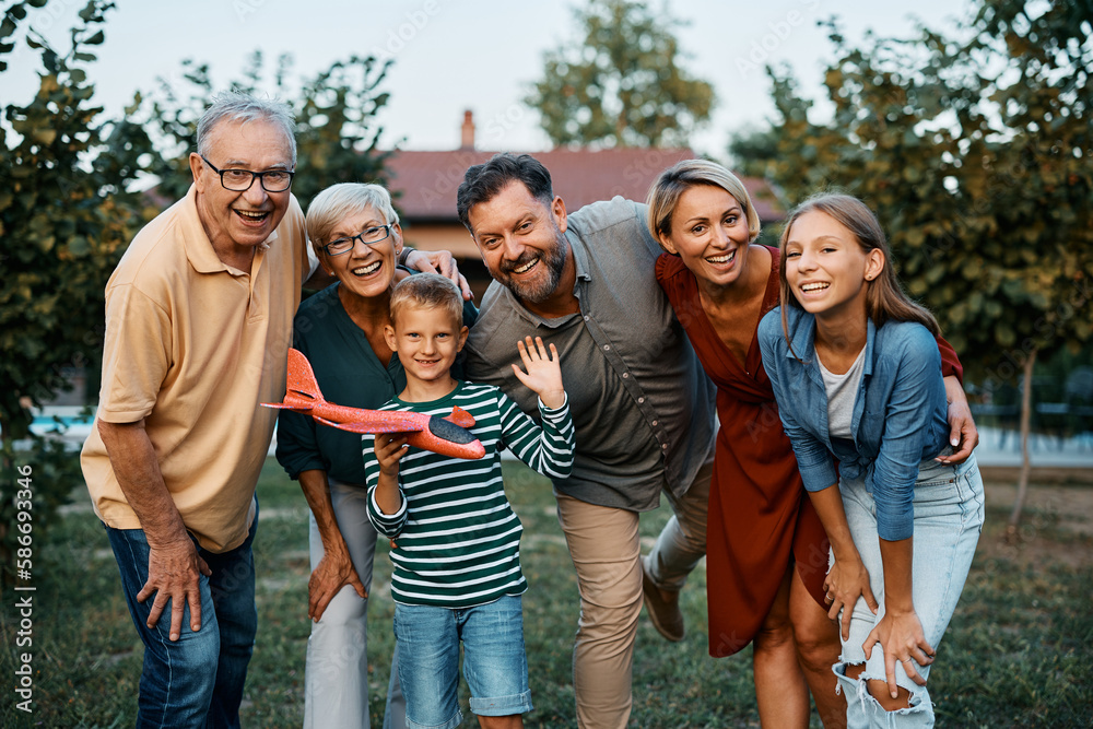 Wall mural Portrait of cheerful extended family in backyard looking at camera.