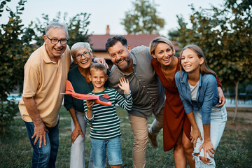 Portrait of cheerful extended family in backyard looking at camera. - obrazy, fototapety, plakaty