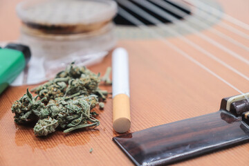 marijuana buds on top of a guitar. hobbies or lifestyle concept