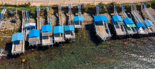 Fototapeta na wymiar Aerial view of the stilt houses of Santa Marinella, in the Metropolitan City of Rome, Italy. These wooden constructions are used for sunbathing by the sea.