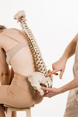 Orthopedist showing spinal column model with girl on white background. Scoliosis is sideways...
