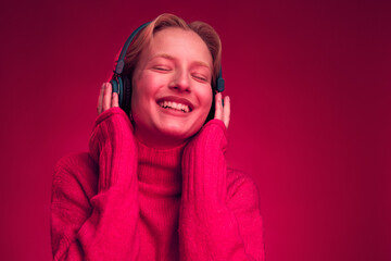 Portrait of a happy woman listening to music isolated on magenta background. Monochromatic picture.