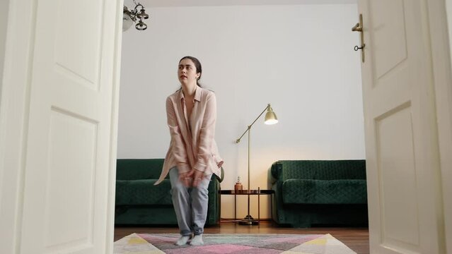 Pretty young Caucasian woman wearing casual clothes learning to charleston in home. Concept of dance training and advertising