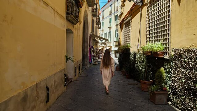 Female tourist walking on the narrow streets in Sorrento, Italy. A young woman exploring beautiful streets with flowers and shops in Europe.