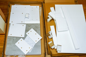 Opened cardboard packaging with new laminated chipboard parts for furniture assembly