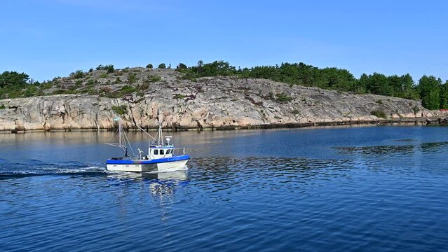Fishing boat sailing through the calm waters of the Swedish coast near Koster island