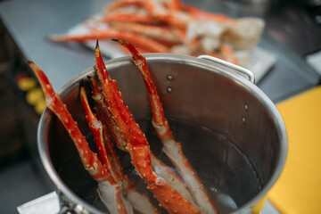 Legs of fresh red Kamchatka crab in a pot of water in the restaurant kitchen. Preparation of fresh...
