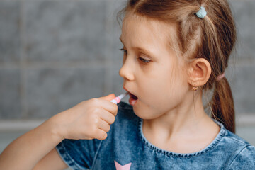 A handsome little girl opens her mouth wide and brushes her teeth. The concept of children's oral care.