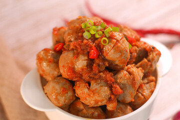 Selective focus of Bakso Mercon (spicy meatballs) on wooden spoon. traditional food from Java, Indonesia, cooked with various herbs.