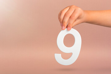 Number nine in hand. A hand holds a white number 9 on a red background. Concept with number nine....