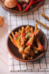 Ceker mercon or claw fireworks a food made from chicken claws cooked with chilies, onions and flavoring. served on clay plate, wooden plate and brown napkin.