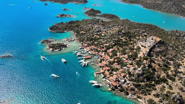 Aerial video of Simena Castle (Kalek&ouml;y), beach, and yachts, highlighting the picturesque coastal landscape and historical significance in Antalya, Turkey.