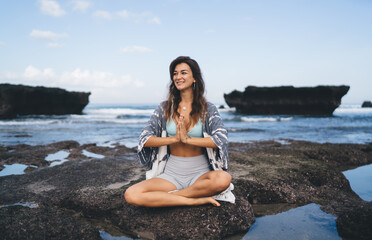 Fototapeta na wymiar Young woman sitting on beach stone in mudra