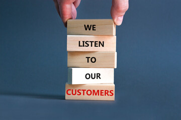 We listen to our customers symbol. Concept words We listen to our customers on wooden block. Beautiful grey background. Businessman hand. Business we listen to our customers concept. Copy space.