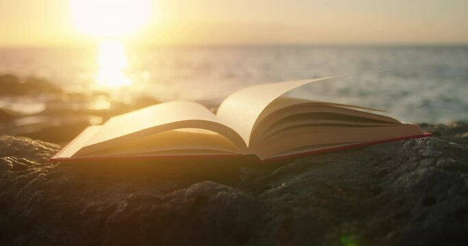 Open book on blurred ocean background. Sea beach at sunset with glow light.
