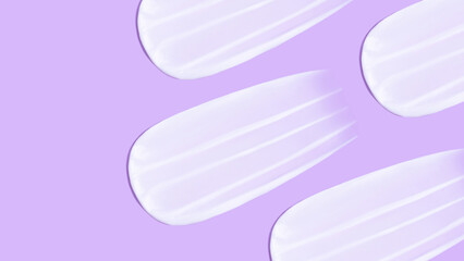 The background is cosmetic. Many smears of cream on a pink purple background