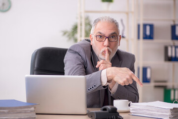 Fototapeta premium Old male employee working in the office