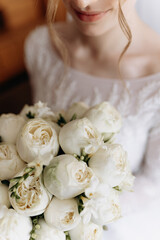 the bride in a dress standing in a green garden and holding a wedding bouquet of flowers and greens