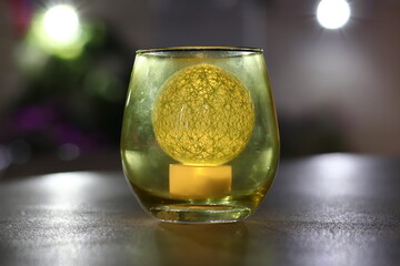 An artificial decorative candle in the shape of a sphere and placed inside a glass