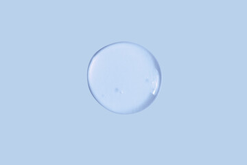 Large round drop of transparent cosmetic gel on a blue, blue background