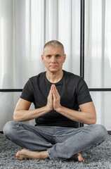 Portrait of a man who meditates in the lotus position on a yoga mat during a break at work.