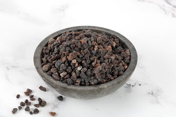 Himalayan crystal black salt in a gray bowl on a white background. Spices background.