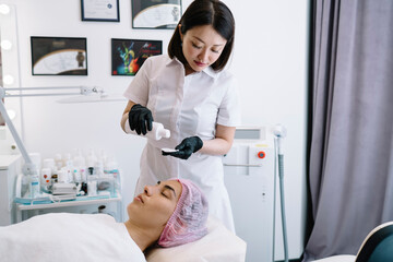 Professional cosmetologist pouring gel on cotton pad preparing for procedure