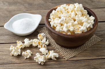 Popcorns on a bowl with salt and soda over wooden table