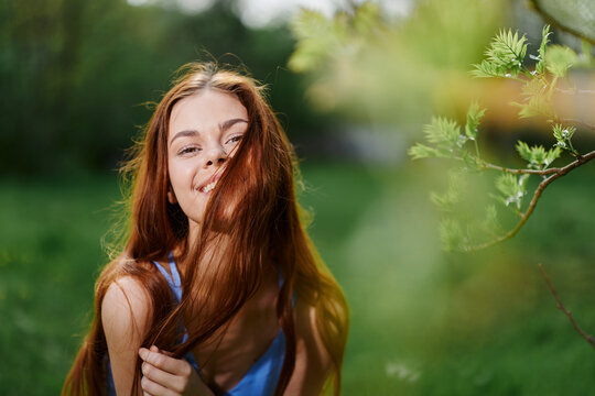 Portrait of a young woman with a beautiful smile in nature on a background of greenery in the spring on a sunny day, the beauty of health and youth, happiness