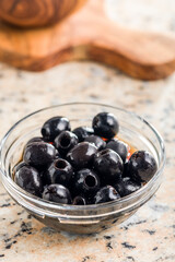 Pitted black olives in bowl on kitchen table.