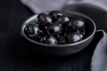 Pitted black olives in bowl on kitchen table.