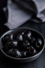 Pitted black olives in bowl on kitchen table.