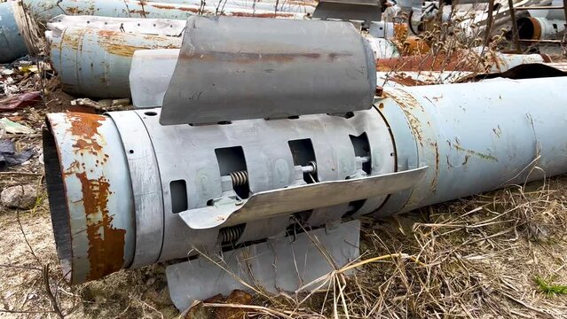 The tail section of the rocket of the Uragan multiple rocket launcher system, lying on the ground in dry grass. The Russian-Ukrainian war. Shelling of peaceful Ukrainian cities