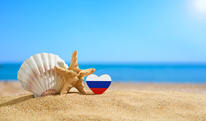 Fototapeta na wymiar Flag of Russia in the shape of a heart and shells on a sandy beach..