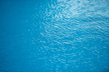 Blue pool water background. Blurred transparent clear calm water surface texture. Water waves in sunlight with copy space.