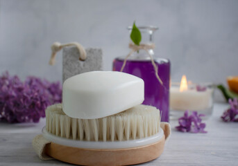 Fototapeta na wymiar Massage brush, lilac flower on a light background
