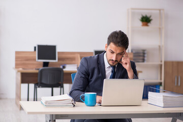 Young male employee sitting at workplace