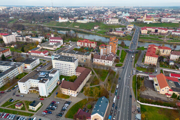 Fototapeta premium Top view of the historical center of the city. Flying a drone over the roofs of houses and a bridge over the river. The long main street of the city during the day.