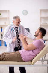 Fototapeta premium Young male patient visiting old male doctor