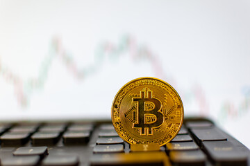 Bitcoin on the keyboard and a graph in the background